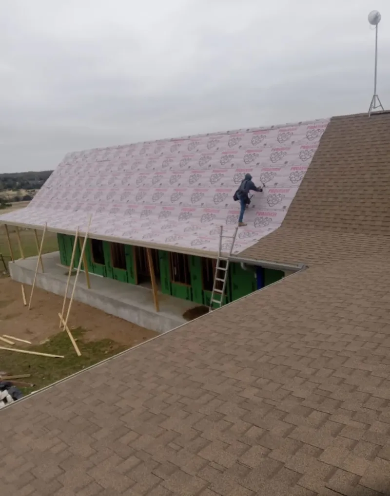 Worker preparing underlayment for a metal roof installation in South Valley